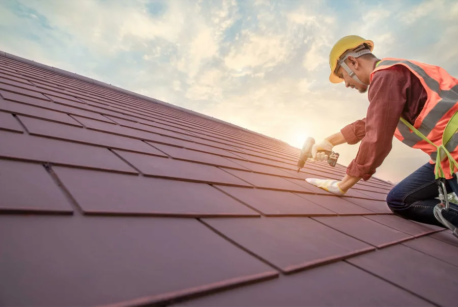 Roofing professional fastening a metal roof system with fall protection