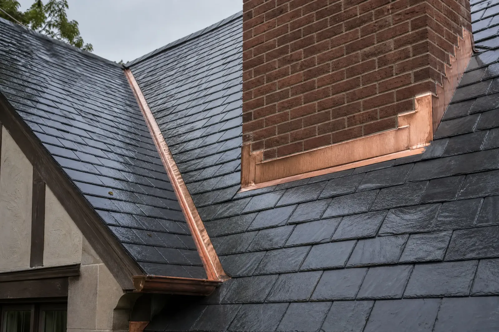 Slate roof with copper chimney flashing and valley transition
